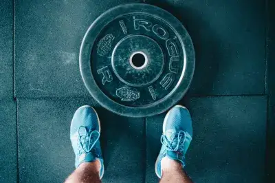 The Best Free CrossFit Apps You Can Download : Black steel gym plate and pair of blue running shoes